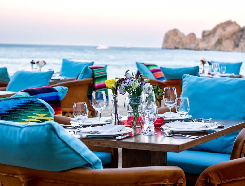Chairs and tables set for dinner by the ocean