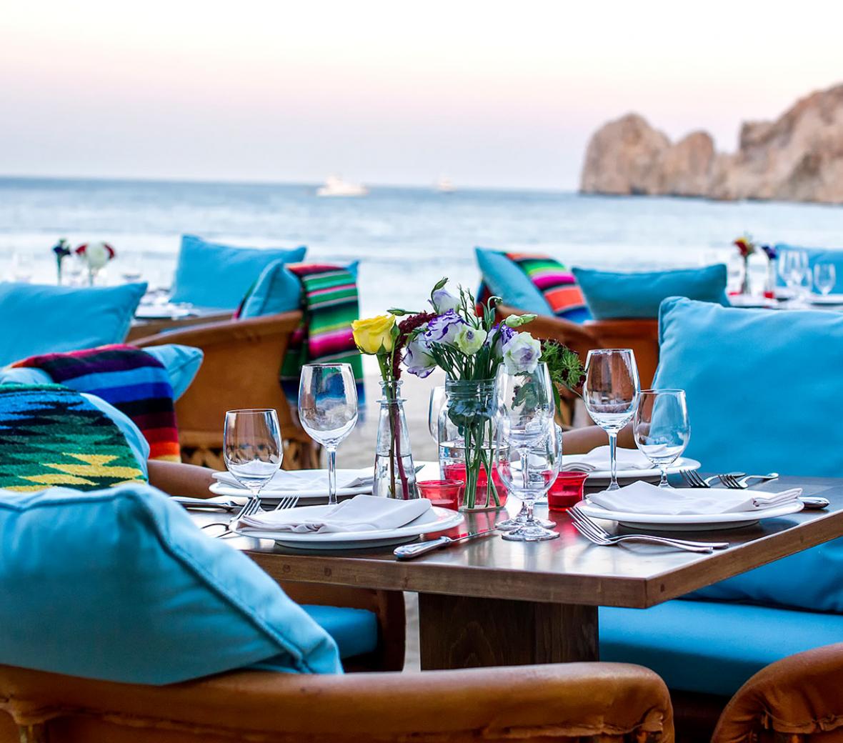 Chairs and tables set for dinner by the ocean