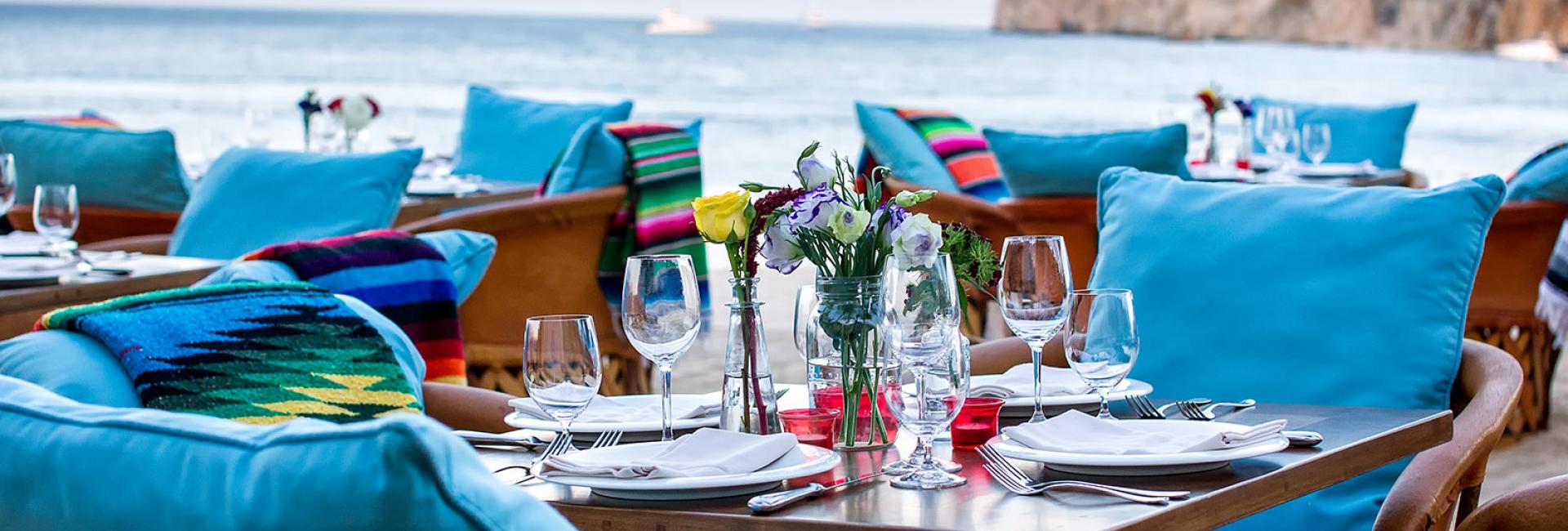Chairs and tables set for dinner by the ocean