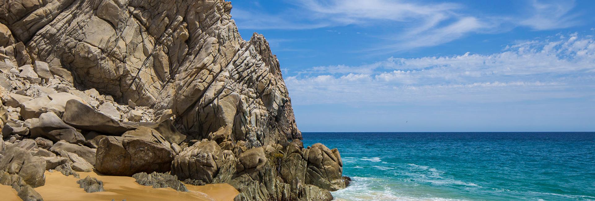 bright blue water and sky against a rocky shore